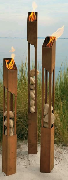 three wooden sculptures with rocks and fire in them