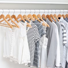 clothes hanging on wooden hangers in a closet