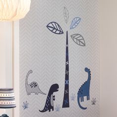 a wall with dinosaurs and trees painted on it's side, next to a lamp