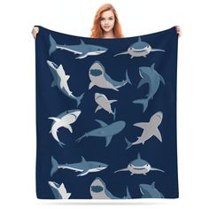 a woman is holding up a blanket with sharks on it