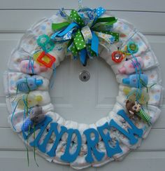 a baby shower wreath is hanging on the front door with its name written in blue