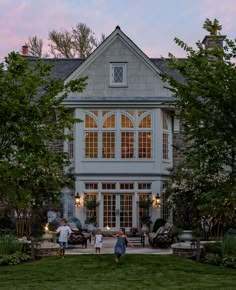 two people standing in front of a large house