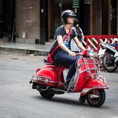 a man riding on the back of a red scooter