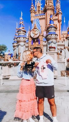 a man and woman taking a selfie in front of the castle at disney world