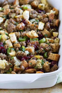 a casserole dish filled with stuffing, cranberries, and other vegetables