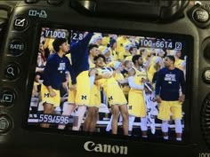 a camera with the image of a group of men in yellow uniforms on it's screen