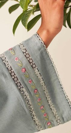 a woman's hand holding onto a green plant with pink flowers and leaves on it