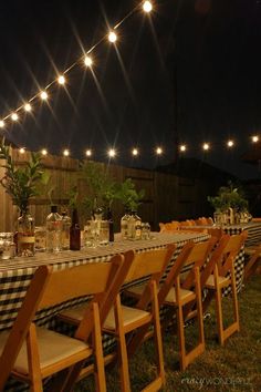 a long table is set up outside at night with lights strung over the tables and chairs