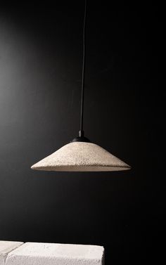 a black and white photo of a light hanging from a ceiling fixture in a dark room