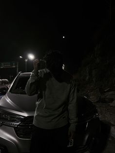 a man standing next to a parked car at night