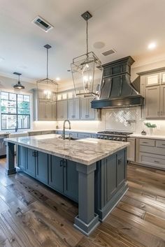 a large kitchen with an island in the middle and two pendant lights hanging from the ceiling