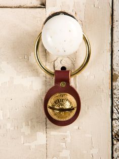 a door handle with a glass ball hanging from it's center ring on an old wooden door