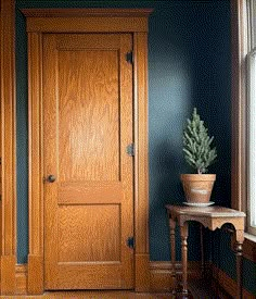 a wooden door in the corner of a room next to a table with a potted plant on it