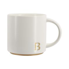 a white coffee mug with the letter b in gold on it's bottom and side