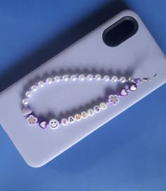 a cell phone case with a beaded name and smiley face on the front, sitting on a blue surface