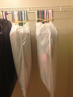 two bags are hanging on the wall next to each other, and one bag is wrapped in plastic