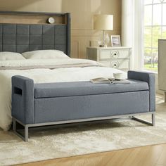 a bed with a blue upholstered foot board and headboard is in a bedroom