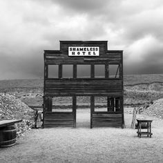 a black and white photo of a wooden structure with a sign that reads shameless boys