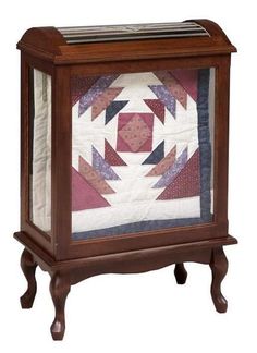 a small wooden cabinet with a quilt on it