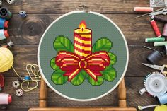 a cross stitch pattern with a candle on it and other sewing supplies around it,