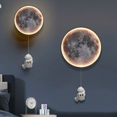 two moon shaped clocks hanging from the side of a wall next to a night stand