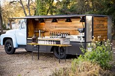 an old truck with a bar in the back is parked near some trees and bushes