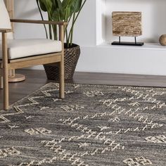 a large rug with an intricate design on the floor in front of a chair and potted plant