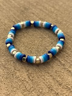 a blue and white beaded bracelet on sand