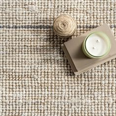 a white candle sitting on top of a rug next to a roll of twine