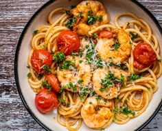 pasta with shrimp, tomatoes and parmesan cheese in a white bowl on a wooden table