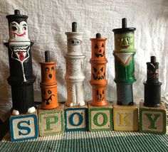 a group of wooden blocks with carved faces and words spelling spooky