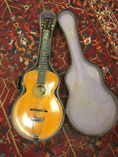 an old guitar laying on top of a rug next to it's carrying case