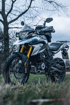 a motorcycle parked in the grass near a tree