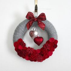 a red and gray wreath hanging on the wall with a heart shaped ornament