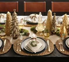 the table is set for christmas dinner with pine trees and napkins on it's placemats