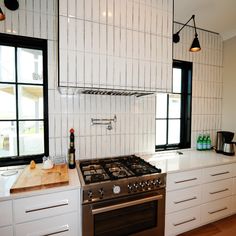 a stove top oven sitting inside of a kitchen next to a counter and two windows