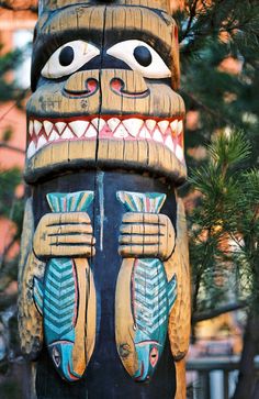 a totema statue is standing in front of a pine tree with its mouth open