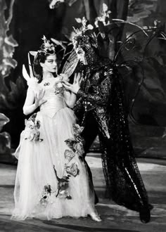 an old black and white photo of two women dressed in costumes, one holding a bird