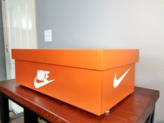 an orange box sitting on top of a wooden table with white nike logo painted on it