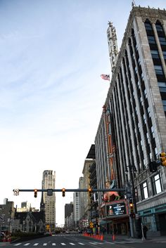 an intersection in the middle of a city with traffic lights and tall buildings on either side