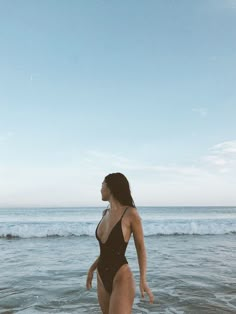 a woman in a swimsuit walking into the ocean