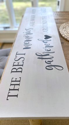 a wooden sign sitting on top of a table next to a rug and window sill