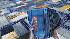 a person holding up a blue book on top of a quilt