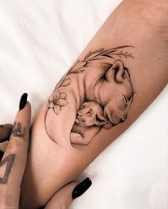 a woman's leg with a tattoo on it that has an image of a baby elephant and its mother