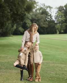 a woman and two children are standing in the grass