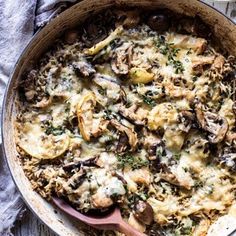 a casserole with mushrooms and cheese in a pan on a table next to a spoon