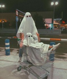 a man sitting in a shopping cart wearing a ghost costume