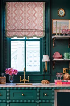 a kitchen with green cabinets and pink flowers in the window sill on the counter