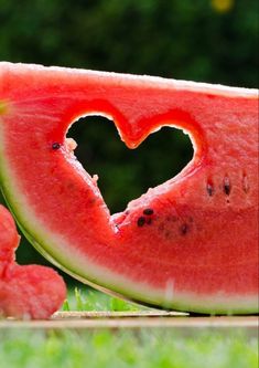 a slice of watermelon with a heart cut out of it sitting on the ground