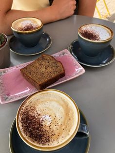 two cups of cappuccino and toast on a table with other coffees